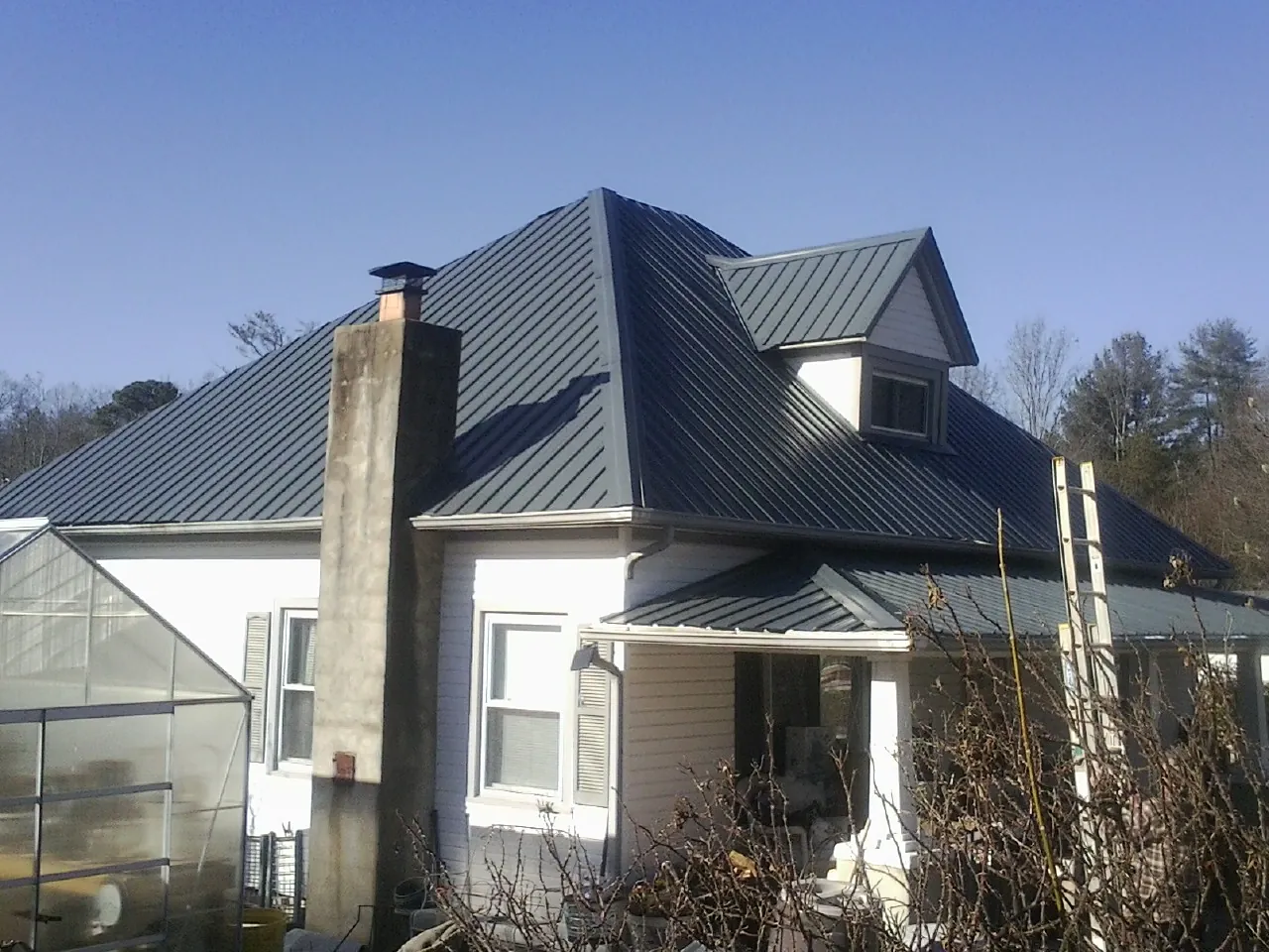 Dark blue standing seam metal roof on a white farmhouse with dormer — Slate & Tile Roof Repair by Roofing Brothers in Schooleys Mountain