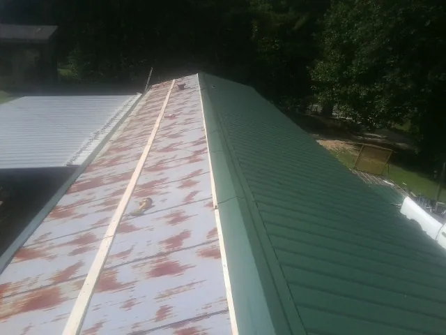 Old rusted panels beside newly installed green metal roofing — Wind Damage Roof Repair by Roofing Brothers in Schooleys Mountain