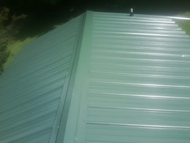 New green metal panels meeting at the ridge of a roof — Flat Roof Repair work by our crew in Schooleys Mountain
