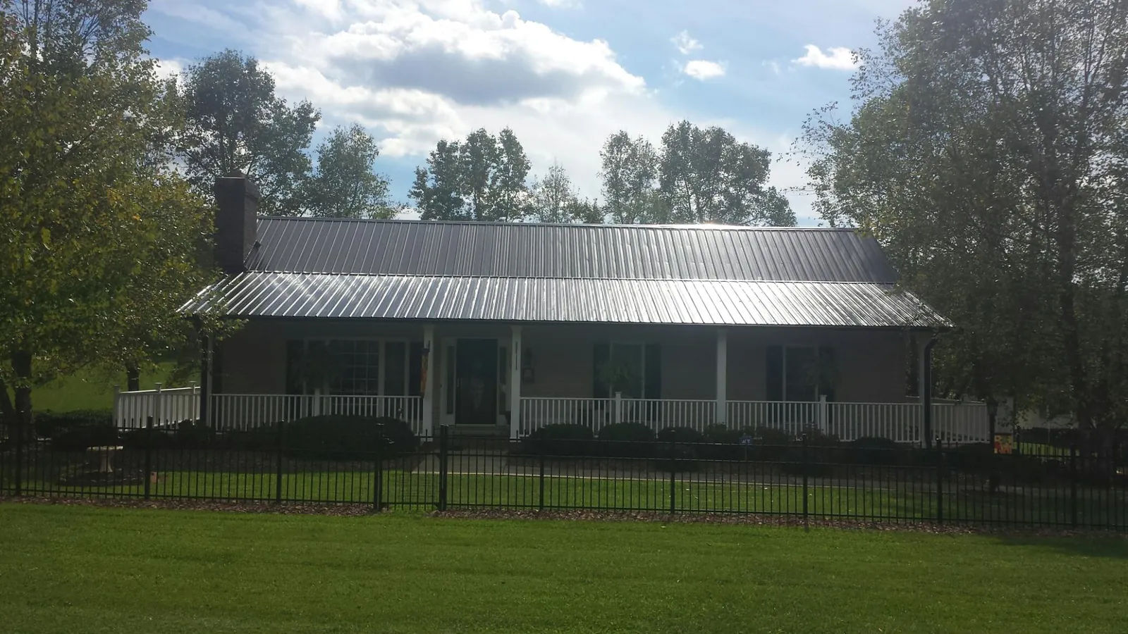 Gray metal roof on a brick ranch with a full width front porch — Gutter Guard Installation work by our crew in Schooleys Mountain