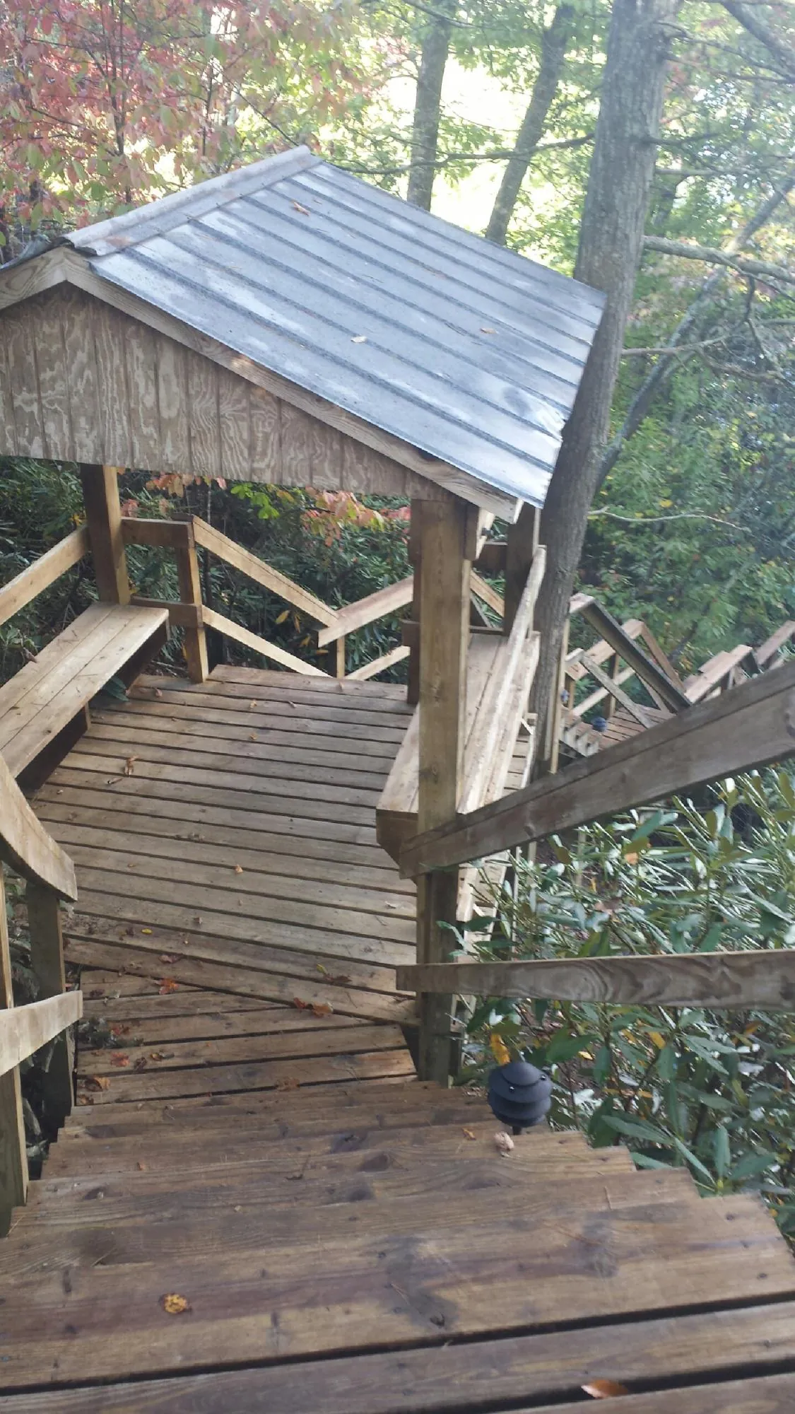 Metal roofed shelter over wooden steps on a wooded walkway — Skylight Repair & Installation work by our crew in Schooleys Mountain