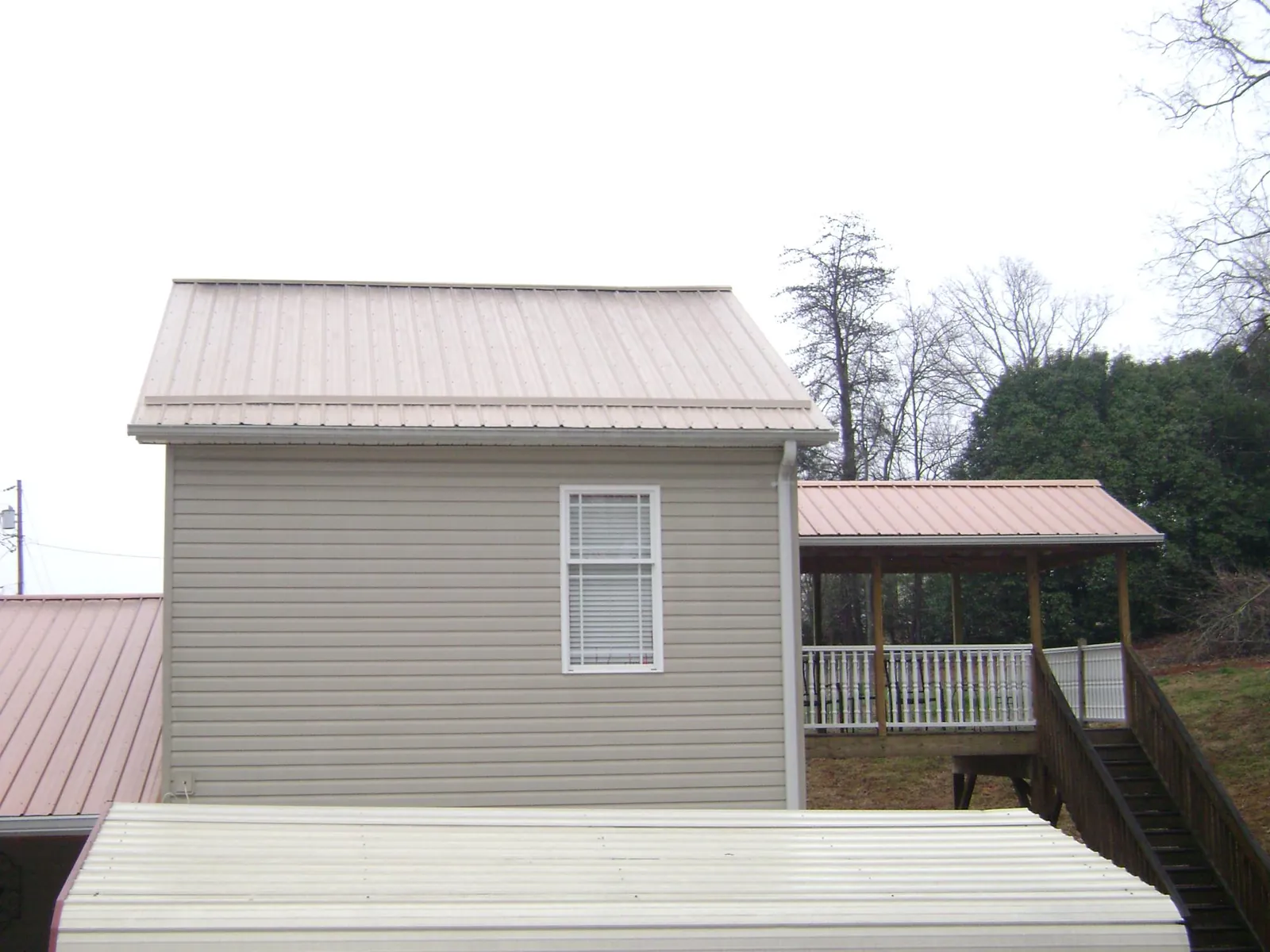 Tan metal roofs on a two story addition and attached porch, from a Roof Replacement job in Schooleys Mountain