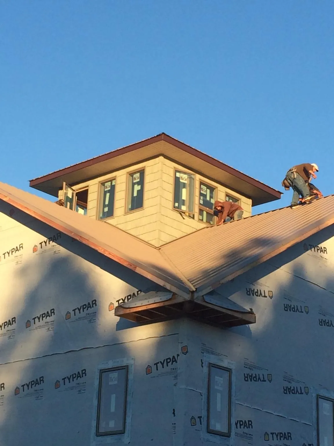 Roofers working around a rooftop cupola on a new metal roof at sunset — Roof Waterproofing in Schooleys Mountain by Roofing Brothers